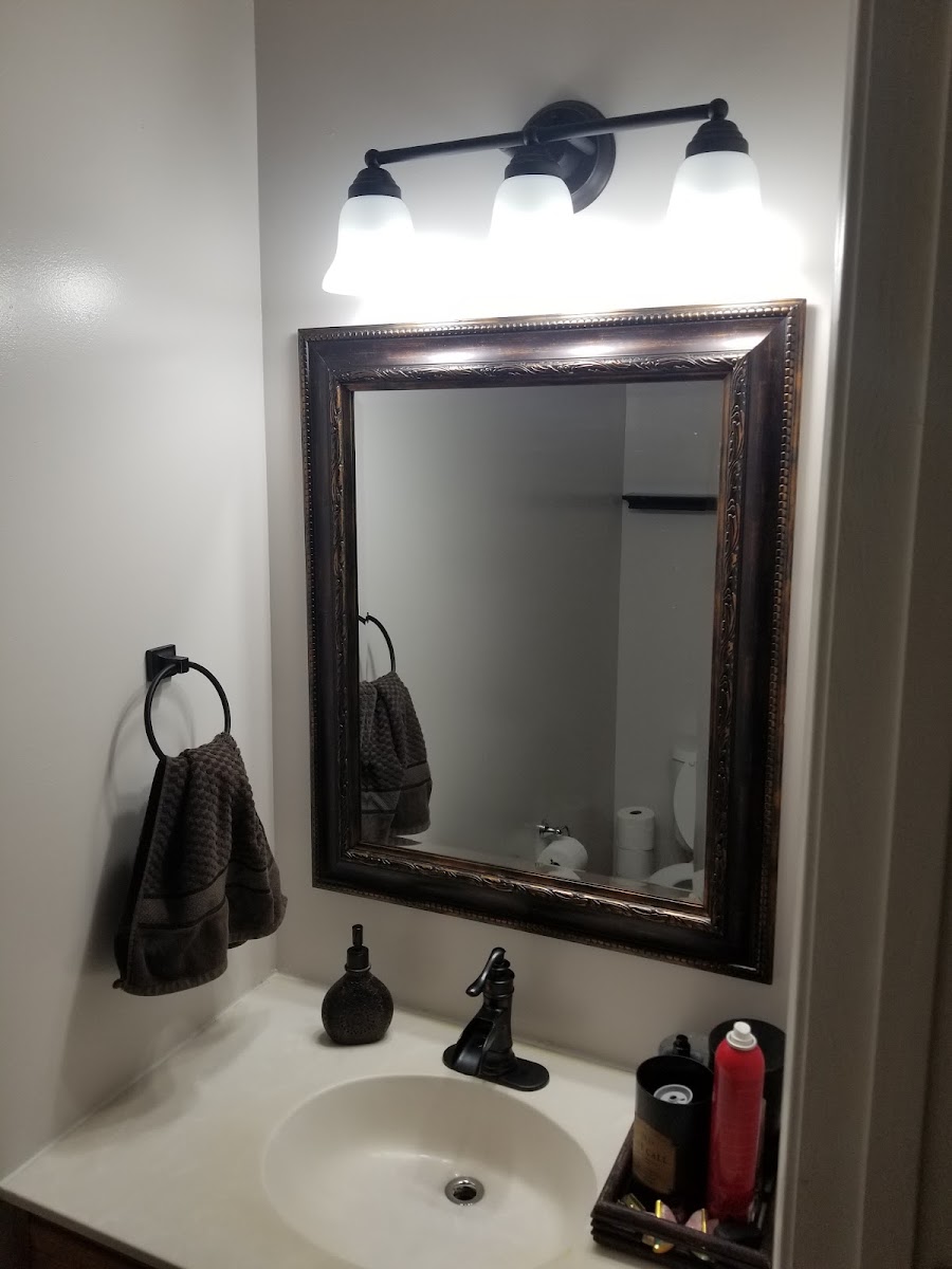 Installed bathroom mirror, lighting, and fixtures