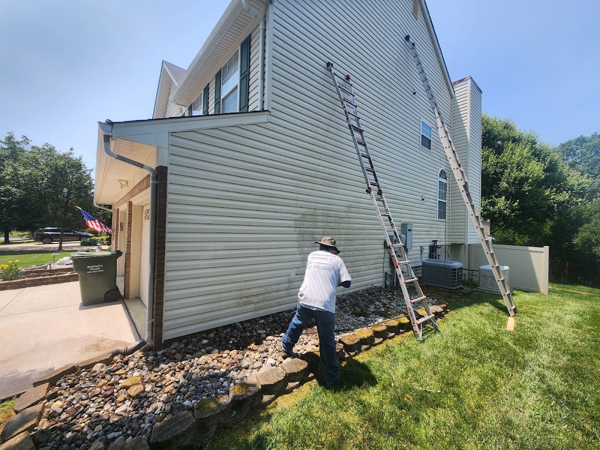 Pressure washing the siding of a two-story home
